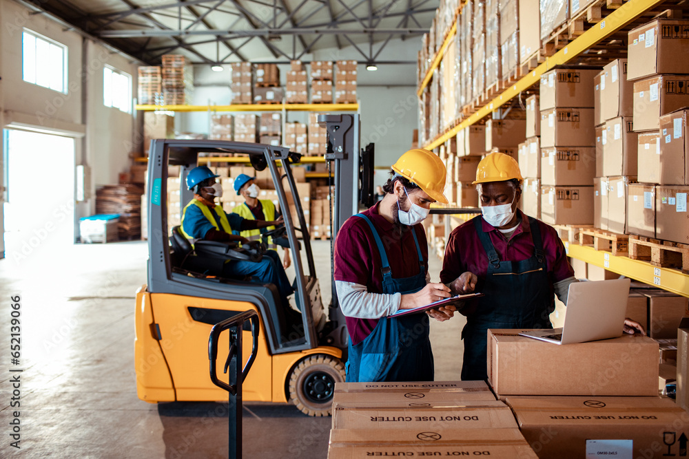 Diverse group of warehouse workers wearing covid19 or coronavirus masks working in a warehouse